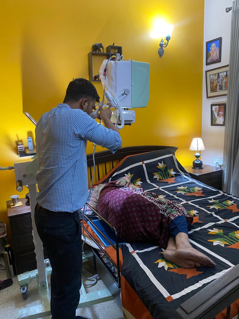Xtra Xray technician operating a portable X-ray unit over a patient at home